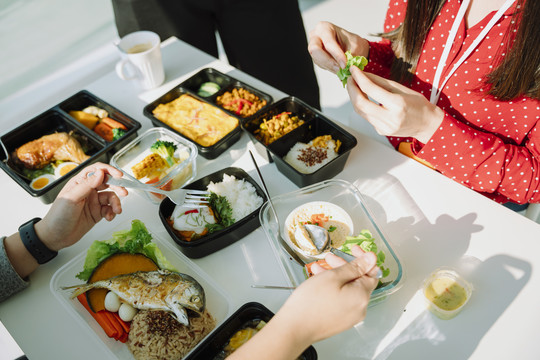 顶视图-人们喜欢在白色的桌子上一起吃健康的食物。提供食物。午餐盒套装。