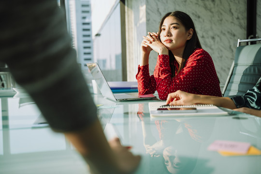 穿着红衫的年轻漂亮的亚泰女商人在会议室听人们讲话。