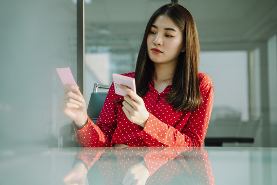 美丽的年轻亚泰女商人在红衫阅读粘不张贴它的关切和担心的表情。