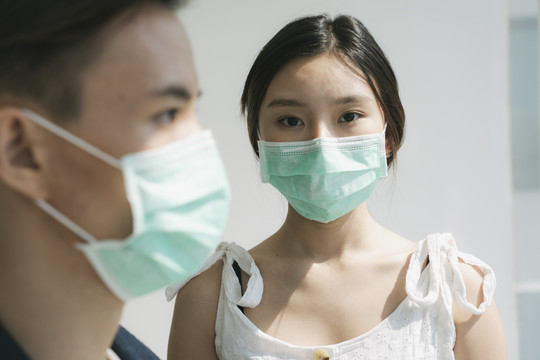 一对戴着医生面具的亚裔夫妇住在房子里。亚洲妻子担心丈夫外出打工。一个戴着医生面具的男人的侧视图。
