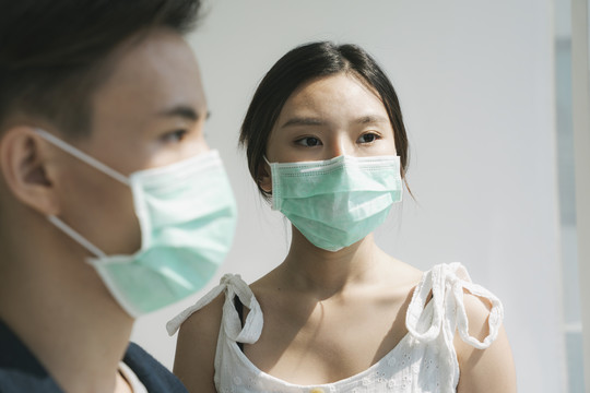 一对戴着医生面具的亚裔夫妇住在房子里。亚洲妻子担心丈夫外出打工。一个戴着医生面具的男人的侧视图。