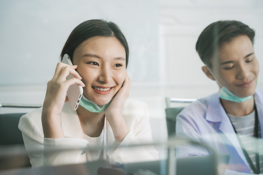 呼叫中心服务-美丽的亚洲女人在医院里打电话回答病人的问题。