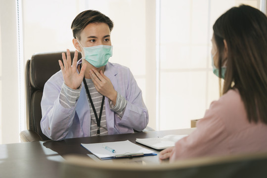 亚泰医生戴口罩在医院或诊所与女病人面谈或交谈。医疗诊断疾病。