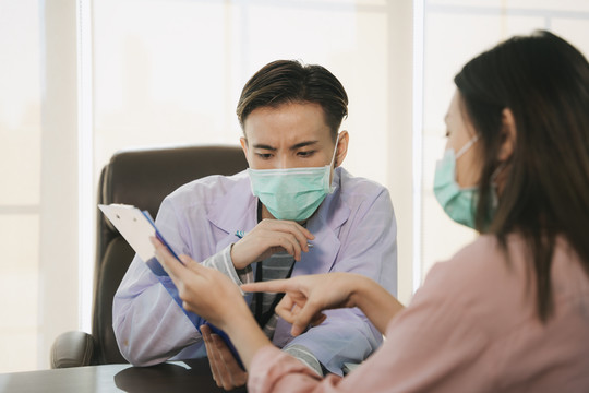 亚泰医生戴口罩在医院或诊所与女病人面谈或交谈。医疗诊断疾病。