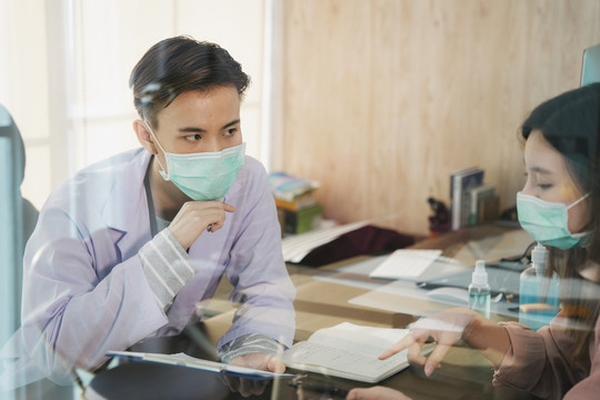 亚泰医生戴口罩在医院或诊所与女病人面谈或交谈。医疗诊断疾病。