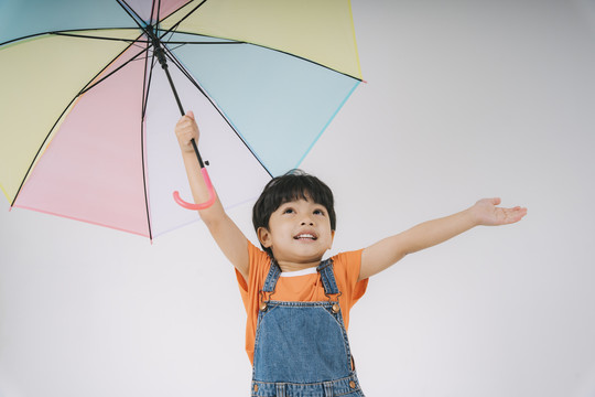 小男孩得到彩色粉彩雨伞时很高兴，他很喜欢雨伞。