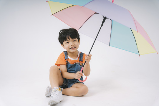 小男孩得到彩色粉彩雨伞时很高兴，他很喜欢雨伞。