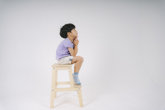 小男孩坐在木椅上，想着他的未来。