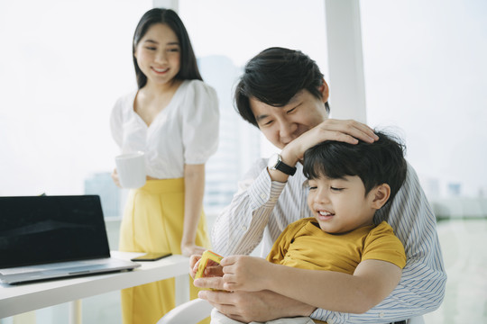 一家人住在城里的公寓里，妈妈接到老板的电话，爸爸教儿子做作业。