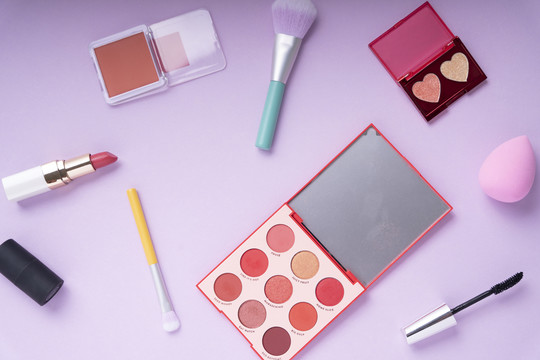 顶视图-紫粉色背景上的Colouful化妆品工具。