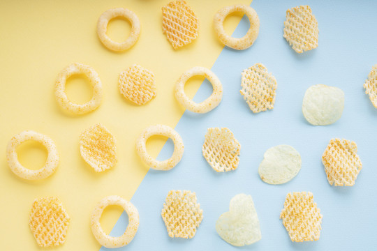 俯视图-黄色和蓝色背景上的多种薯片。