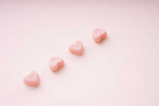 顶视图-粉红色背景上的四颗心形糖果。