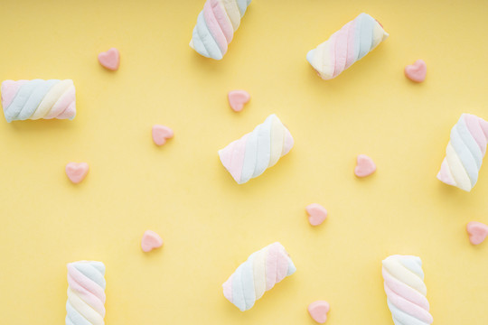 顶视图-黄色背景上的心形彩色彩虹，香醇甜美的糖果。