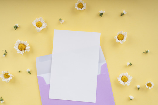 在黄色背景和白色花朵上，用紫色字母附上的模拟白纸。顶视图。