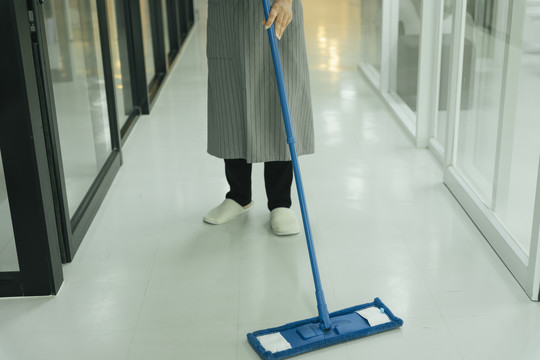 女佣用拖把清洁公寓房间的地板。