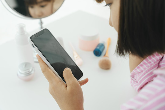 美丽的年轻亚泰黑人短发女子在洗手间使用智能手机。