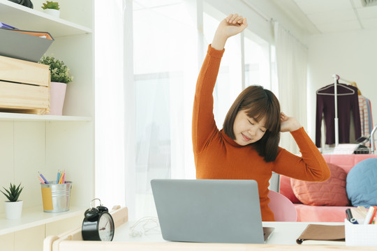 美丽的年轻亚泰黑人短发女子伸展双臂后在家学习完。