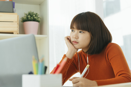 年轻漂亮的亚泰黑短发女子厌倦了在家拿笔记本学习。