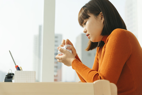 侧视图-美丽的年轻亚泰黑人短发女子双手揉纸。愤怒的艺术家。