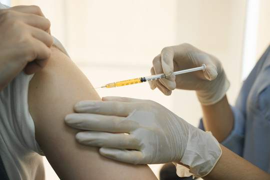 医生通过在手臂和肩膀注射疫苗来帮助被covid-19病毒感染的人。