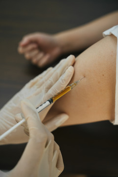 医生通过在腿部注射疫苗来帮助被covid-19病毒感染的人。