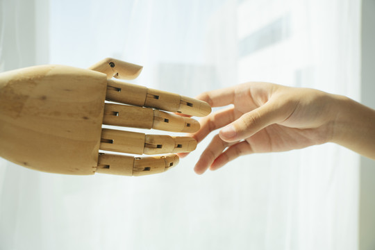 木制半机器人的手和人类握手的手。