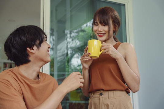 亚洲夫妻家庭快乐。美丽的妻子给在家工作的丈夫带来一杯热咖啡。新常态。爱与关怀。