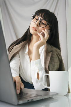 商务亚泰长黑发女子戴眼镜用笔记本电脑。在家工作的概念。