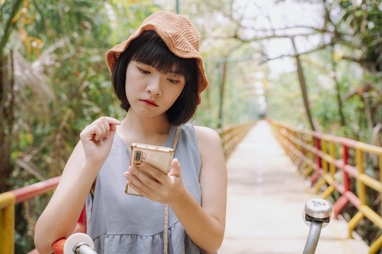 年轻的泰国亚裔女性在旅行中不再骑自行车，而是在智能手机上看地图。本地旅行。