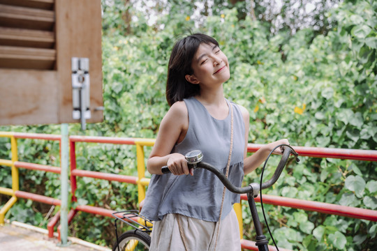 年轻的泰国亚裔女子在乡村小街骑自行车。本地旅行。