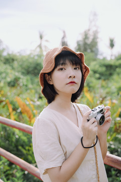 美丽的泰国亚裔女子深色短发摄影师在大自然中用胶卷相机拍照。