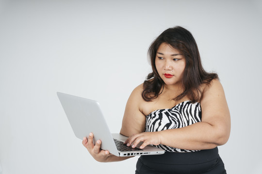 亚洲胖乎乎的女商人在白色背景下使用笔记本电脑的肖像。