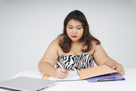 亚洲胖女人在白色背景的办公桌上拿着文件。