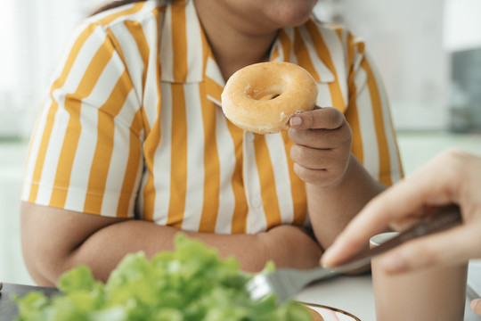 肥胖的商业女性午餐吃不健康的甜甜圈。