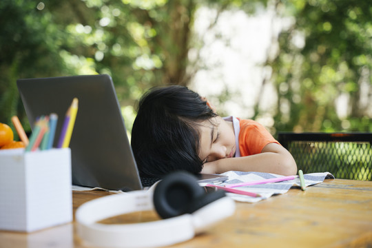 亚洲小孩厌倦了在笔记本电脑前学习。