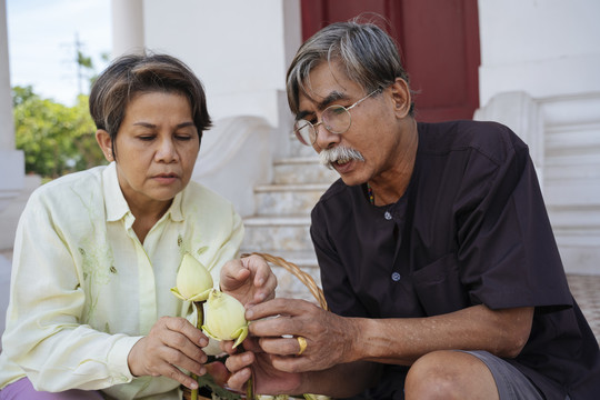 亚洲老年夫妇在庙里准备莲花功德。
