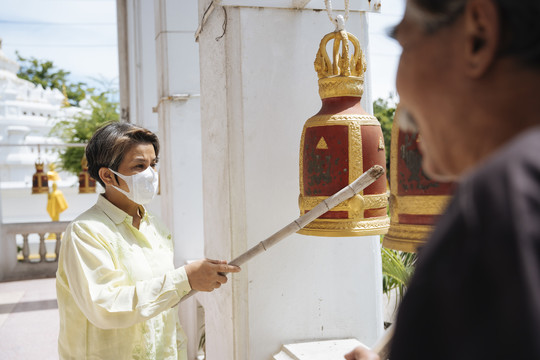 亚洲老年夫妇在泰国寺庙敲钟许愿。