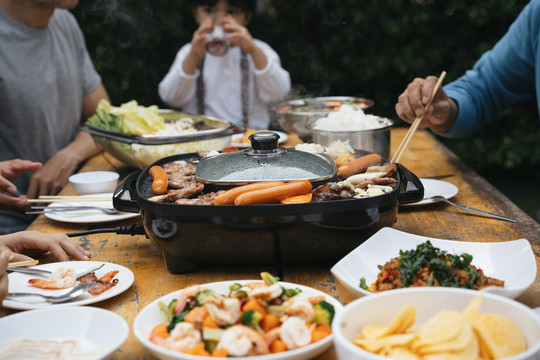 亚洲人一家人喜欢在户外的院子里一起吃烧烤。