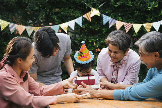 快乐的亚洲家庭在户外院子里一起庆祝孩子的生日聚会。