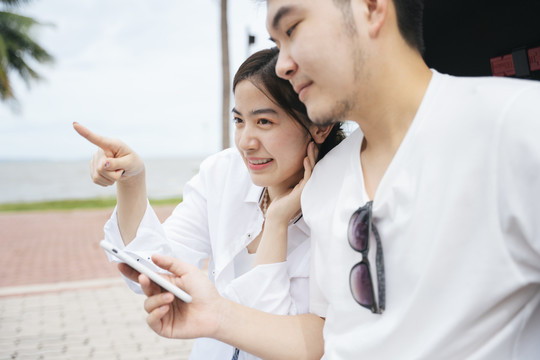 在户外使用智能手机地图应用程序的亚洲旅行情侣。