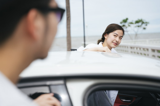 一位亚洲女旅行者在上车前看着她的男朋友。一对夫妇准备去旅行。