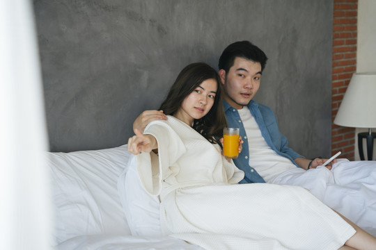 亚洲情侣旅行者在酒店卧室放松。