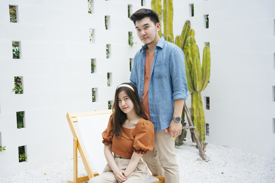 一对亚洲夫妇的时尚肖像，蓝色牛仔裤夹克，白色背景上有橙色衬衫。