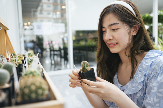 美丽的亚洲女农场主手持仙人掌壶。