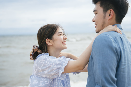 迷人的亚洲情侣在沙滩上拥抱。