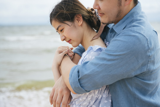 迷人的亚洲情侣在沙滩上拥抱。