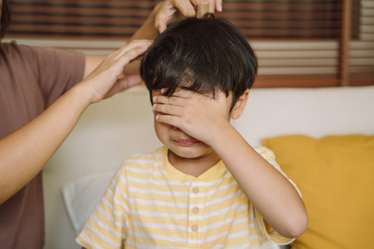 哭泣的亚洲男孩用手捂着脸，母亲试图让他好起来。欺负和抑郁压力或沮丧。