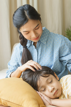 特写亚洲男孩睡在母亲的腿在家里。