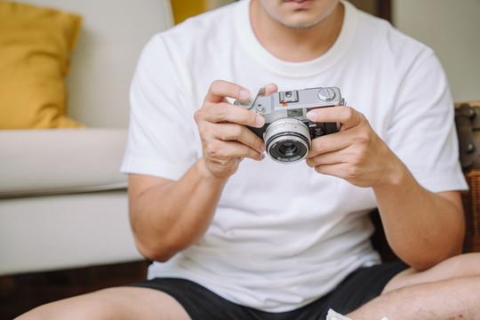 特写镜头-一个穿着白衬衫的男人双手拿着相机。