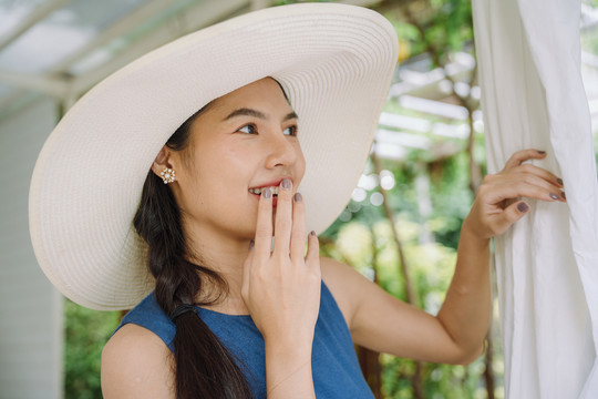 在度假酒店戴大帽子的亚洲女人的肖像。大自然中的女旅行者。